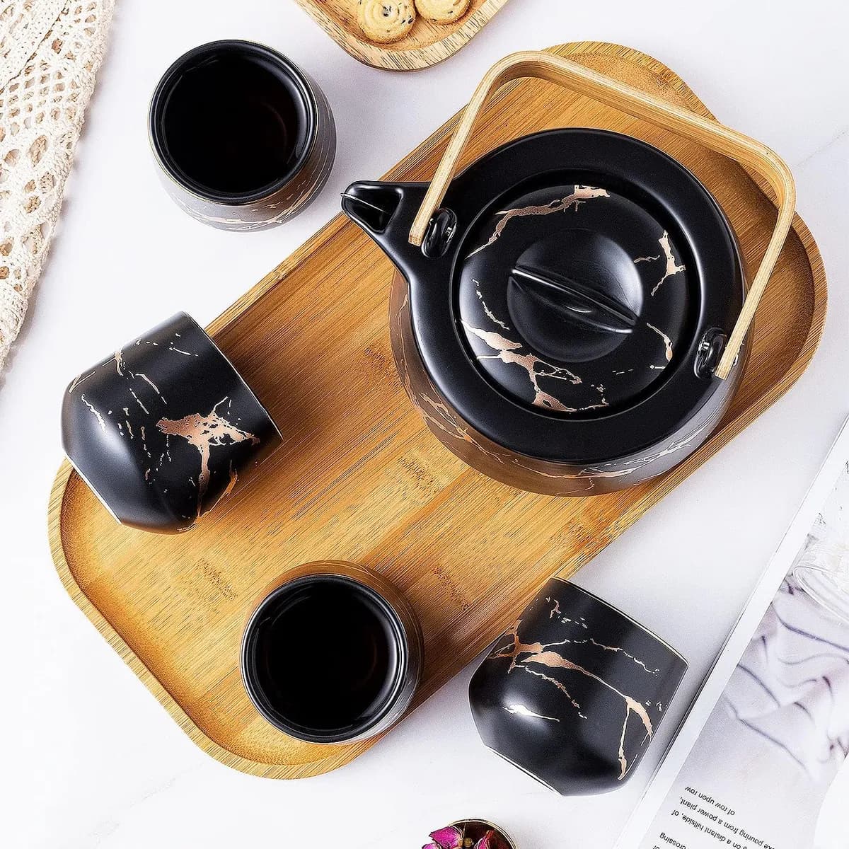 Vista cenital del juego negro con tetera y tazas sobre bandeja de bambú